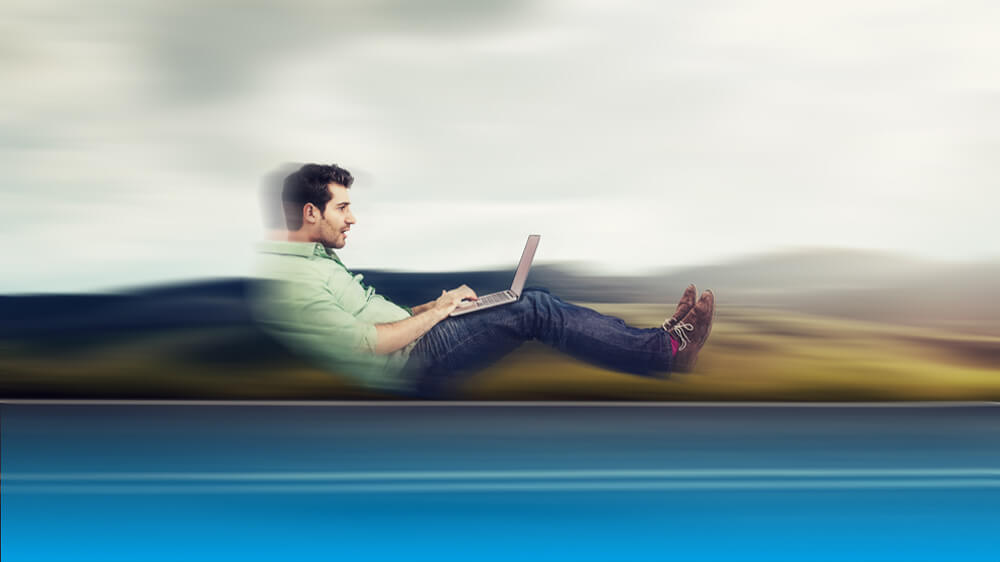 person sitting, leaning back, looking at laptop, made to look as if they are traveling fast