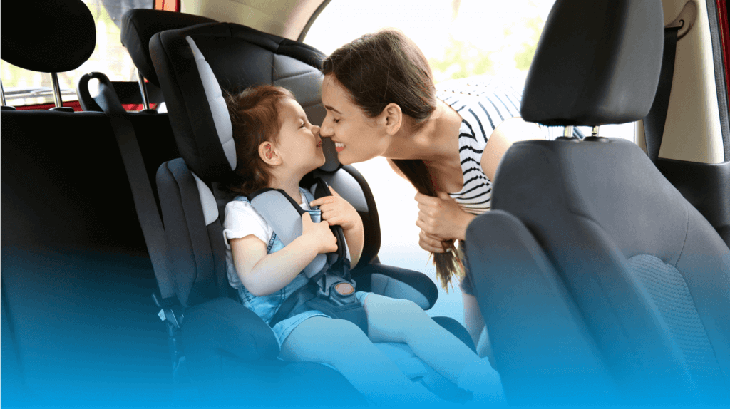 mother kissing baby in car seat