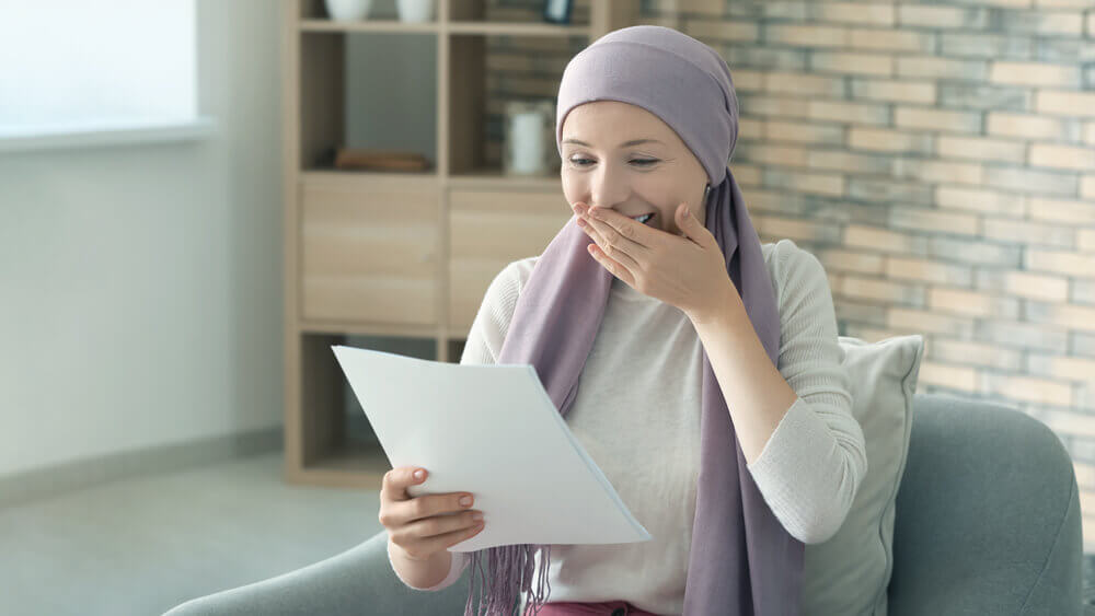 woman wearing headscarf looking at paper, very happy