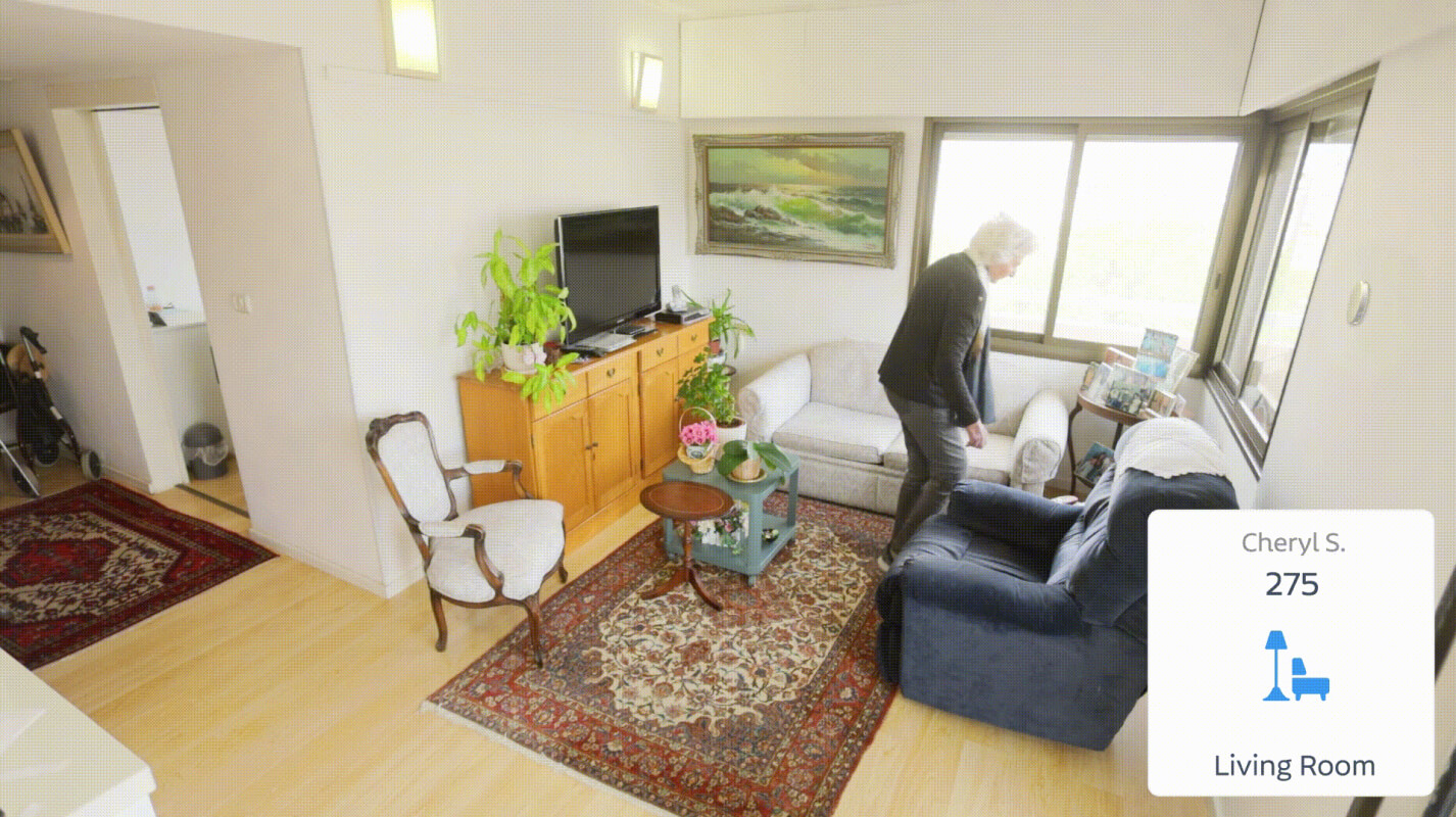 Senior woman in living room, virtual card showing "Cheryl S., 275, Living Room"