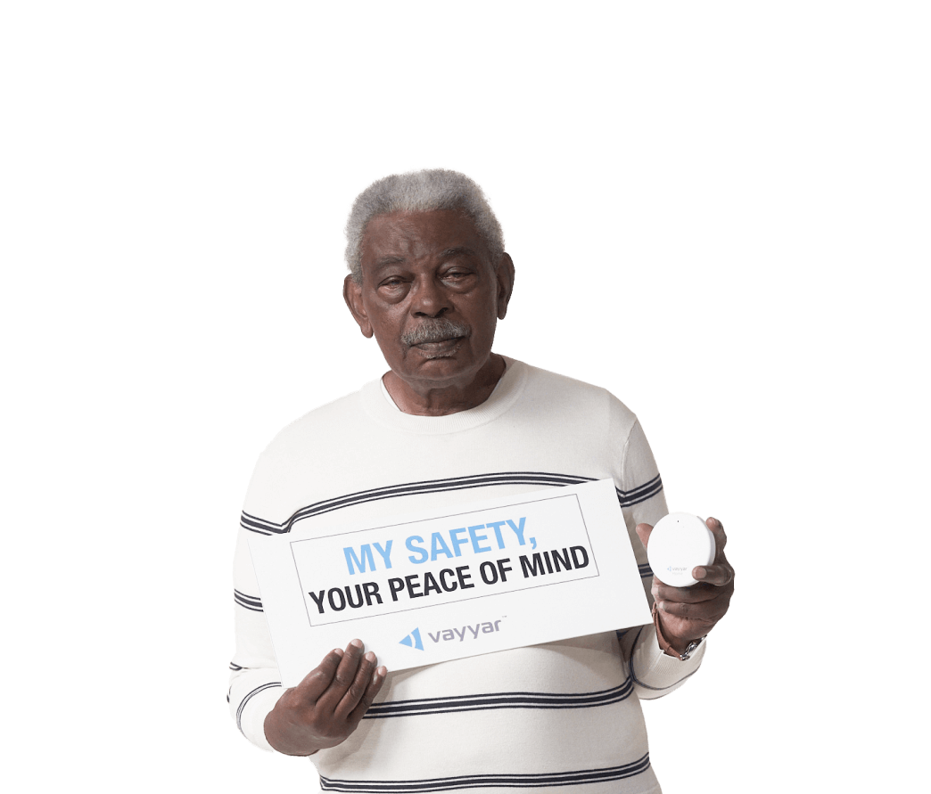 senior man holding VayyarCare device and sign that says "My safety, your peace of mind"
